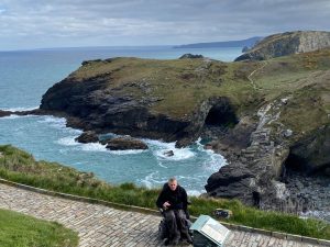 Nick Carr in front of Tintagel castle, wiwth dramatic scenery behind