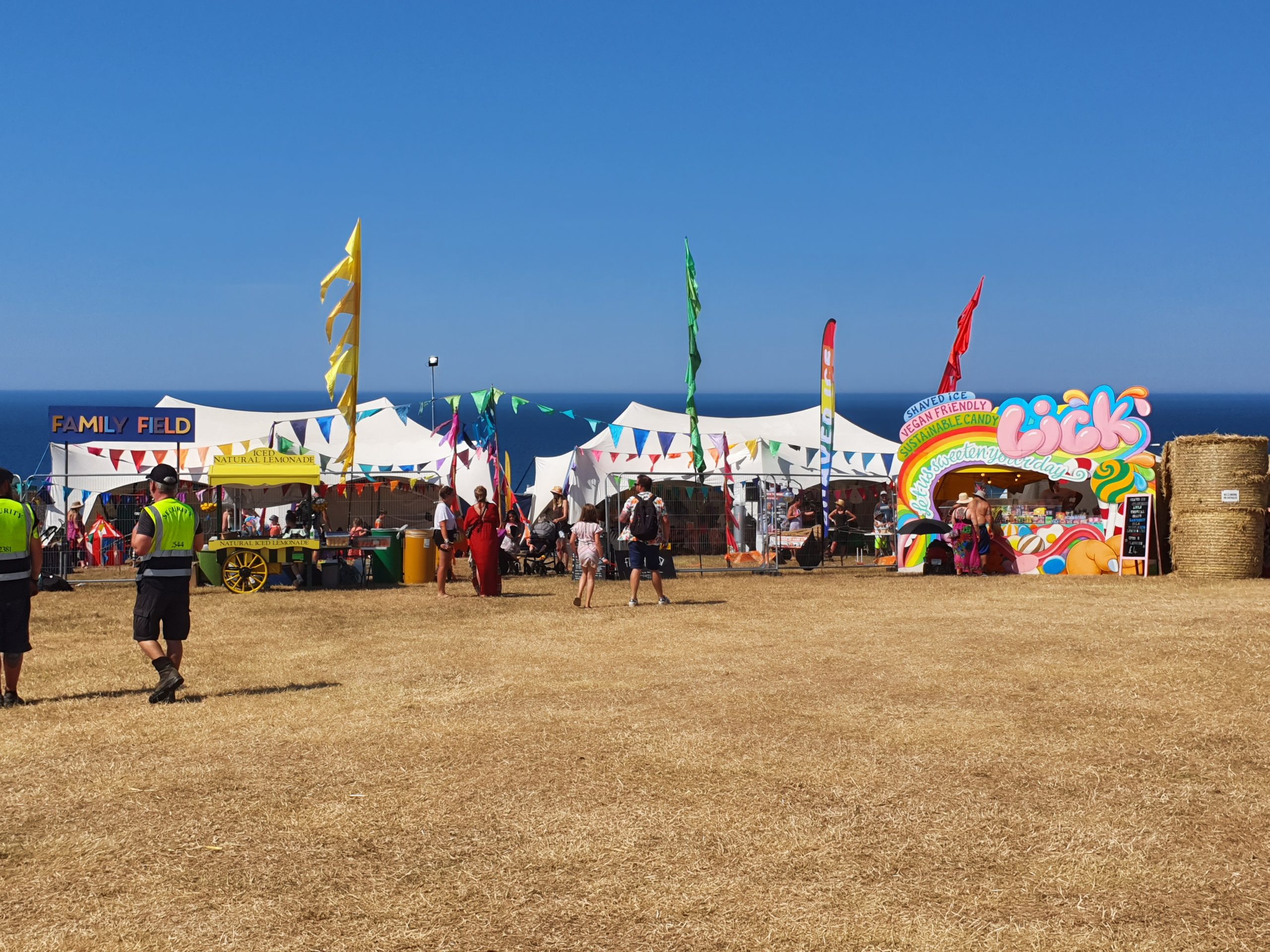 the family field, lots of festival goers, two family tents and 3 multicoloured flags and various bunting