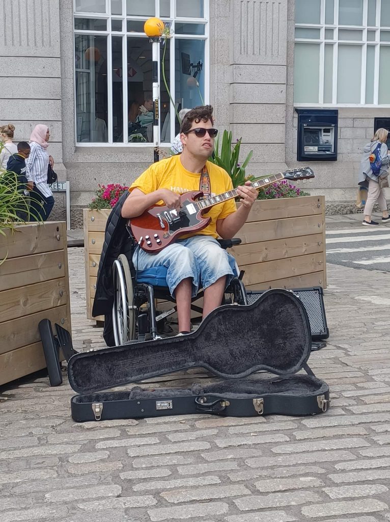 Oliver Busking, playing electric guitar and looking cool in sunglasses