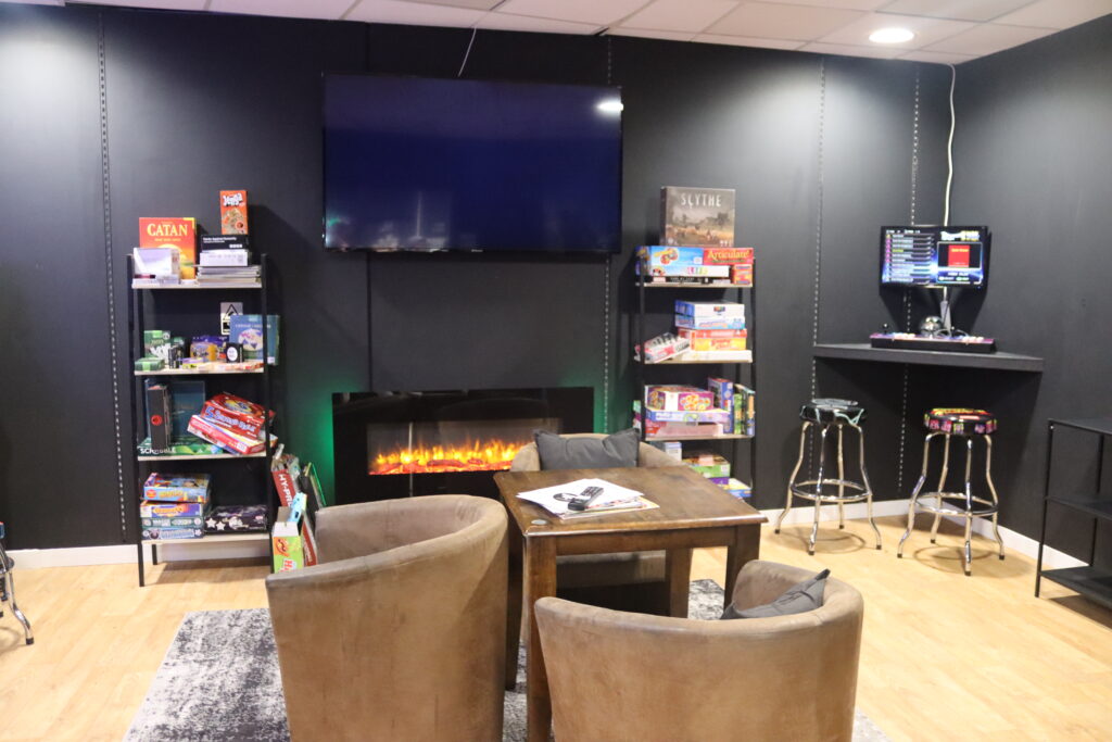 The V.I.G room. shown is a private area with seating, a host of board games, a huge TV , an electric fire and a side bar with stool seating and a retro games machine