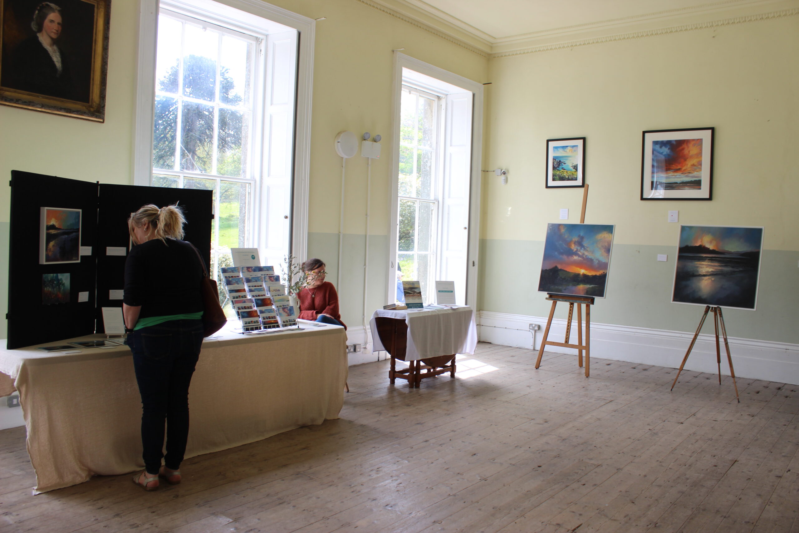 Oil paintings on display in a large, spacious room, filled with daylight from the large windows at Enys House during the 2024 Bluebell Festival and Art Exhibition. Artworks are vivis oil paintings by Rachel Painter 