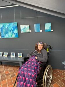 Holly sat in her wheelchair, proudly next to her art work gallery display