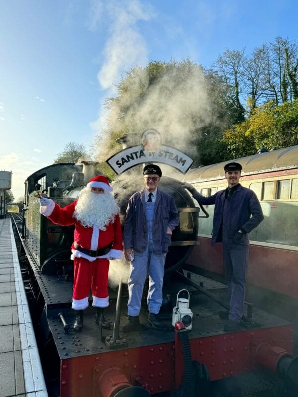 Santa stood with two train drivers on the front of a steam train