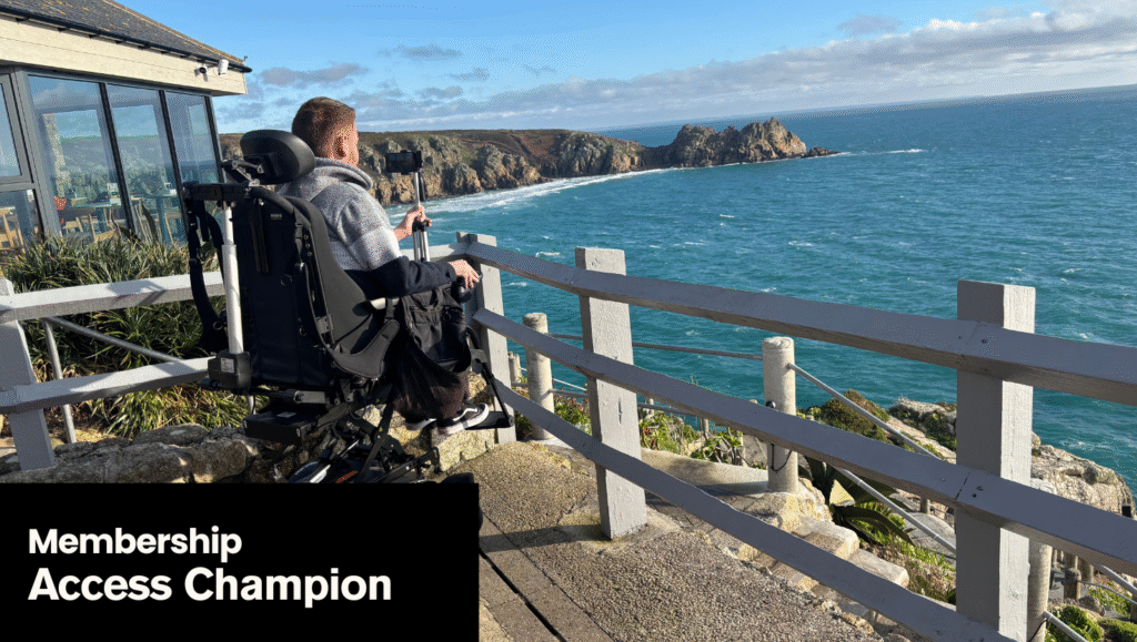 A photo of a wheelchair user looking out over teh sea at the Minack Theatre in Cornwall. The text on the image says Membership: Access Champion