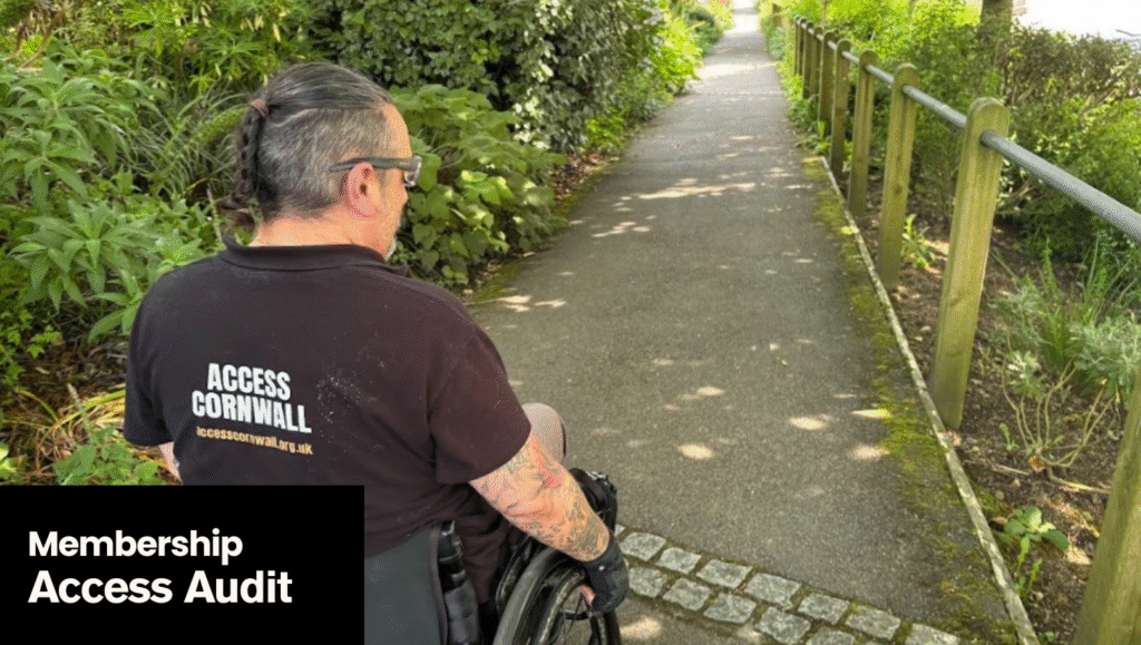 An Access Cornwall auditor wearing a T shirt with Access Cornwall is moving down a path at the PK Porthcurno Telegraph museum. Membership: Access Audit